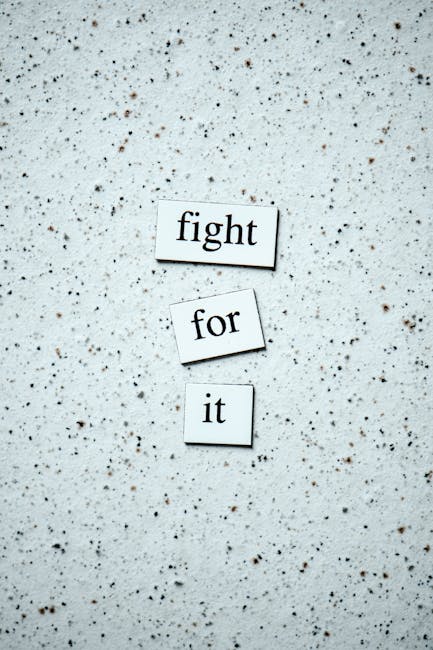 The image shows three cut-out paper words arranged vertically on a speckled, light-colored surface. The top word is 'fight,' the middle word is 'for,' and the bottom word is 'it,' together forming the phrase 'fight for it.' The background appears to be a textured, possibly terrazzo or speckled concrete surface, with no other objects or materials visible. This arrangement of words can metaphorically relate to determination or effort, themes often associated with home relocation or the process of moving, aligning subtly with house removals and furniture transport services provided by Man with Van Colindale.